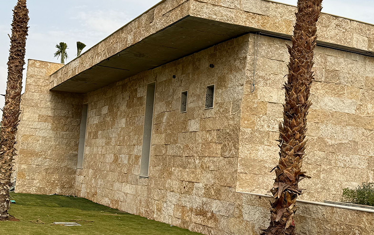 Warm textured stone building beside a planted garden